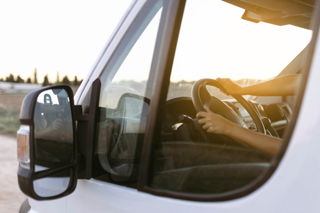 View from the outside of the steering wheel of a van and woman hands at sunset before starting the trip